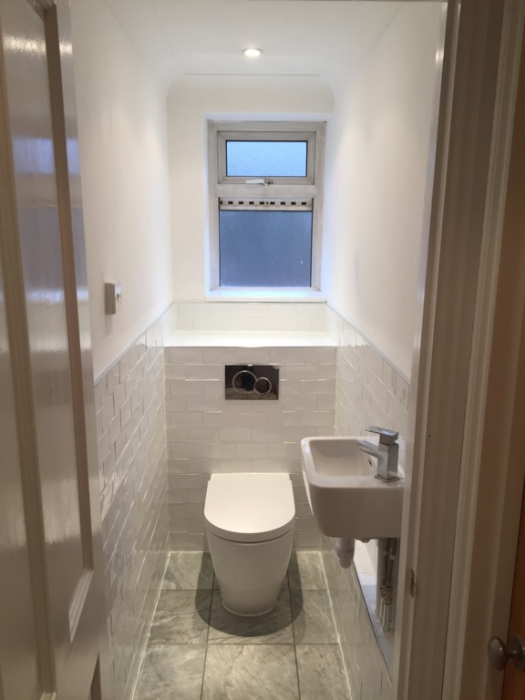 Downstairs toilet renovation, featuring tile floor, part tiled wall, integrated toilet and sink