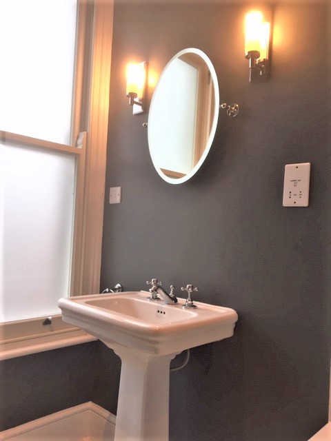 Victorian style bathroom featuring sink, mirror and wall lights